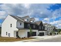 View of townhomes featuring a mix of white and charcoal exteriors, gabled roofs, and single-car garages at 206 Sharon Ln, Loganville, GA 30052