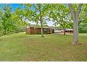 Wide view of a brick home with well-maintained lawn, mature trees and covered carport at 7783 Cantrell Rd, Douglasville, GA 30135
