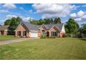 Charming brick home with attached garage, a manicured lawn and a long driveway at 7095 Valley Landing Ct, Cumming, GA 30041