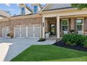 Inviting front of a brick home with a three-car garage, covered porch and nicely landscaped yard at 2470 Crimson Downs Dr, Cumming, GA 30040