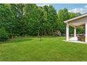 Expansive backyard with lush green grass, mature trees, and covered patio at 2358 Well Springs Dr, Buford, GA 30519