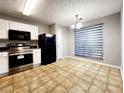 Eat-in kitchen featuring white cabinets, black appliances, tile flooring, and ample natural light at 2430 Piering Dr, Lithonia, GA 30038