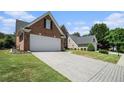 A wide driveway leads to the brick home with an attached two-car garage, complemented by verdant landscaping at 725 Windsor Place Sw Cir, Grayson, GA 30017