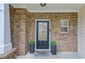 Inviting front door with decorative glass, flanked by potted plants and a brick facade at 2725 Sedgeview Way, Buford, GA 30519