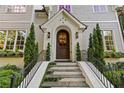 Welcoming front door with classic arch, decorated with a wreath, framed by two matching evergreen topiaries at 1201 Beech Valley Ne Rd, Atlanta, GA 30306