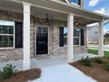 Inviting front porch with classic black door, white columns, and elegant exterior lighting at 1107 Kingston Hill Dr, Loganville, GA 30052