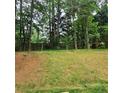 Grassy backyard slopes gently uphill to the tree line and wooden fence at 5859 Bellingrath Way, Lithonia, GA 30058