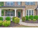 Charming front porch with stone accents, white railings, and lush landscaping at 134 Johnston Farm Ln, Woodstock, GA 30188