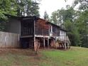 Back exterior showcasing the screened porch, brick foundation, and surrounding trees at 135 Golden Hills Dr, Woodstock, GA 30189
