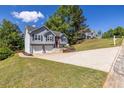 Exterior view displaying a two-story home with a well-kept lawn and driveway, situated on a sloping lot at 1215 Smoke Hill Ln, Hoschton, GA 30548