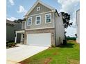 Two-story home features a two-car garage, gray siding, and well-maintained front lawn at 4495 Buttonwood Ln, Lilburn, GA 30047