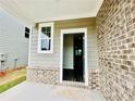 Covered front porch featuring a gray brick facade, entrance door, and small window at 4495 Buttonwood Ln, Lilburn, GA 30047