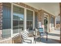 Comfortable seating on the brick front porch, framed by dark shutters and decorated with a wreath at 5015 Montes Ln, Cumming, GA 30040