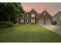 Charming two-story brick home with a lush green lawn and two-car garage at sunset at 2955 Pleasant Valley Trl, Cumming, GA 30028