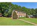 Brick townhome on a lush green lawn with mature trees and a clear blue sky at 373 Dixie Ct, Lawrenceville, GA 30046