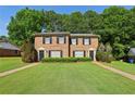 Brick townhome featuring a well-manicured lawn, black shutters, and mature trees in the background at 373 Dixie Ct, Lawrenceville, GA 30046