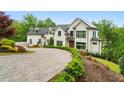 Beautiful white home with black trim, set in a lush green landscape and circular driveway at 1285 Stuart Rdg, Johns Creek, GA 30022