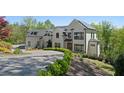 Beautiful white home with black trim, set in a lush green landscape and circular driveway at 1285 Stuart Rdg, Johns Creek, GA 30022