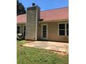 An outdoor space features a chimney, back door, patio and a patch of green grass on a sunny day at 75 Oak Hill Dr, Covington, GA 30016