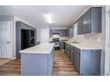 Well-lit kitchen featuring gray cabinets, a center island, and modern black appliances and wood-look flooring at 12237 Cypress Ln, Fayetteville, GA 30215