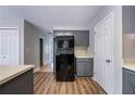 Galley kitchen featuring gray cabinets, black appliances, light countertops and wood-look flooring at 12237 Cypress Ln, Fayetteville, GA 30215