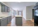 Well-lit kitchen with gray cabinets, light countertops, stainless steel sink, and a view into the adjacent living room at 12237 Cypress Ln, Fayetteville, GA 30215