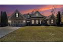 A brick facade single-story home features arched windows and a spacious green front lawn at sunset at 448 Hanover Drive, Villa Rica, GA 30180