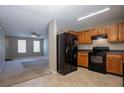 Open concept kitchen with black appliances and wooden cabinets overlooks a bright and open living room at 4812 Browns Mill Ferry Rd, Lithonia, GA 30038