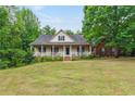 Charming home with a covered front porch, green lawn, and mature trees around the property at 418 Whisper Wood Way, Locust Grove, GA 30248