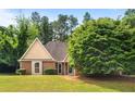 Charming single-story home featuring a brick and tan siding exterior with a well-maintained lawn and mature trees at 221 The Esplanade Se Way, Loganville, GA 30052