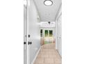 Hallway with tile flooring leading to a sunroom filled with natural light from large windows at 221 The Esplanade Se Way, Loganville, GA 30052