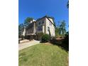 Attractive multi-story brick townhome with manicured lawn, driveway, and mature trees in the background at 288 Blue Pointe Ct, Suwanee, GA 30024