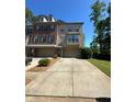 Attractive multi-story brick townhome with manicured lawn, driveway, and mature trees in the background at 288 Blue Pointe Ct, Suwanee, GA 30024
