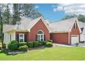 Exterior view of the brick home showcasing lush green lawn, shrubbery and two-car garage at 1010 Capella Creek Way, Grayson, GA 30017