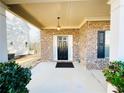 Inviting brick front porch featuring a black door, white columns, and elegant overhead lighting at 2378 Misty Ivy Ct, Buford, GA 30519