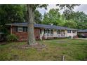 Single-story home features a brick facade, a covered front porch, and a large tree in the front yard, offering shade and curb appeal at 8053 Duralee Ln, Douglasville, GA 30134
