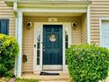 Charming front door with a 'Welcome' wreath and manicured shrubs, creating an inviting entryway at 220 Baltimore Ave, Stockbridge, GA 30281