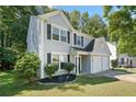 Side view of a charming two-story home with a two-car garage and manicured lawn, set among mature trees at 4104 Glenaire Nw Way, Acworth, GA 30101