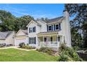 Charming two-story home boasts a well-kept lawn, a covered front porch, and mature trees at 7155 Bannister Park Ln, Cumming, GA 30028