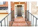 Inviting brick front entrance with a black door, decorative plants, and iron railings at 10090 Jones Bridge Rd # 2, Alpharetta, GA 30022