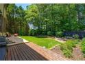 This large backyard showcases a spacious deck and lush, green lawn surrounded by trees at 3680 Milton Park Dr, Alpharetta, GA 30022