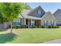Well-maintained front yard features lush green grass, mature tree, and manicured shrubbery at 2906 Jones Phillips Rd, Dacula, GA 30019