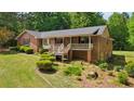 Brick home featuring a covered porch, mature trees, and landscaped yard at 19 Margrit Ct, Stockbridge, GA 30281