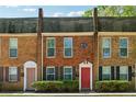 Charming brick townhome exterior with a red front door and well-maintained landscaping at 135 N North River Dr # G, Atlanta, GA 30350