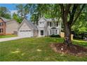 Charming two-story home with a well-manicured lawn and attached two-car garage, complemented by mature trees at 5320 Taylor Rd, Alpharetta, GA 30022