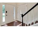 Bright foyer showcasing a stylish front door with sidelights, wood floors, and staircase with a black railing at 5320 Taylor Rd, Alpharetta, GA 30022