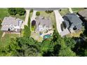 Breathtaking aerial view of a home with a private pool and hot tub surrounded by lush greenery and neighboring houses at 3740 Duckcove Way, Cumming, GA 30041