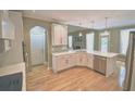 Well-lit kitchen features stainless steel appliances, white cabinetry, and beautiful hardwood floors at 3740 Duckcove Way, Cumming, GA 30041