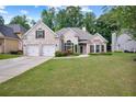 Lovely white brick home featuring a well-manicured lawn, double garage, and classic architectural details at 492 Thorn Creek Way, Dallas, GA 30157