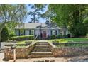 Inviting home featuring stone steps, a red front door, a well-manicured lawn, and beautifully landscaped surroundings at 382 Lofton Nw Rd, Atlanta, GA 30309